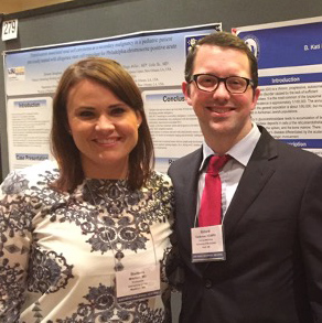 Two smiling Med-Peds residents standing in front of presentation poster.